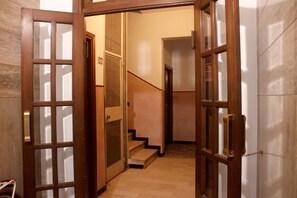 Un couloir avec des portes en bois et un escalier menant à une autre pièce.