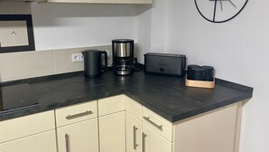 A kitchen with a black countertop, a coffee maker, a toaster, and a clock on the wall. - Stilvolles Designappaetment mit Terrasse & Garten im Idylischem Bindlach (Bindlach)