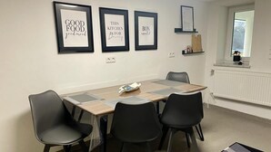A dining area with a wooden table, four black chairs, and three framed signs on the wall. - Stilvolles Designappaetment mit Terrasse & Garten im Idylischem Bindlach (Bindlach)