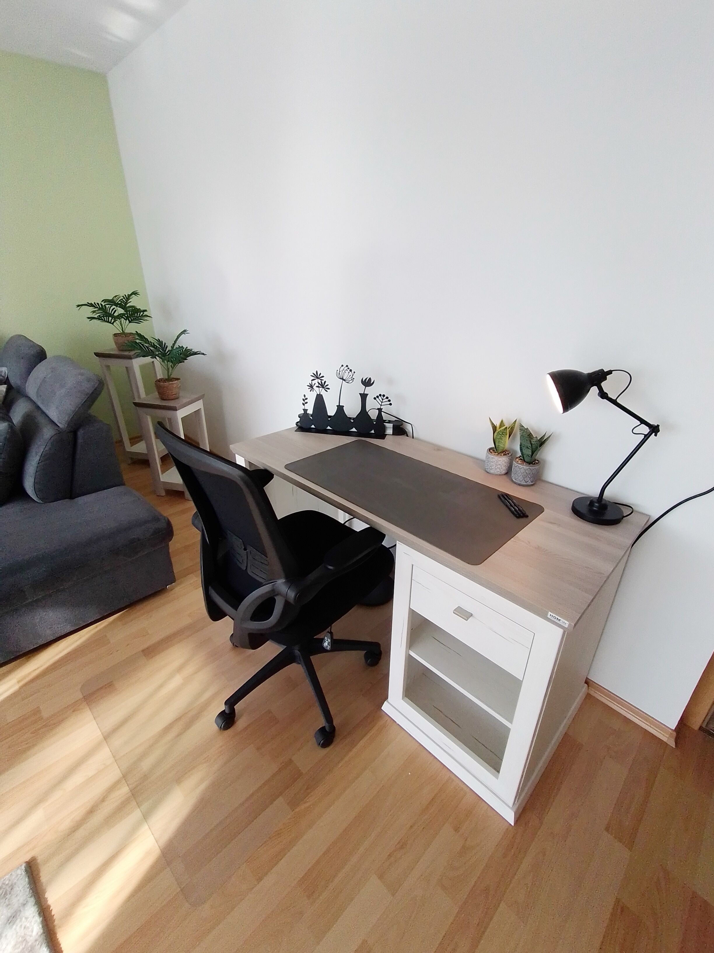 A modern office space with a desk, office chair, and a small table with plants.
