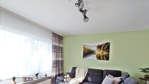 Una sala de estar moderna con un sofá modular, una mesita de centro y un amplio ventanal con cortinas.