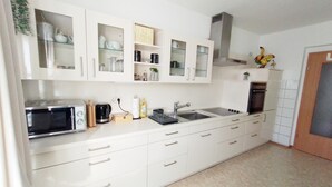 Una cocina moderna con armarios blancos, microondas integrado, un lavaplatos y una estufa.