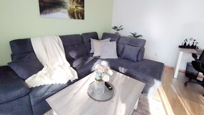 Una sala de estar con un sofá gris, una mesa de centro con un florero y un cuadro en la pared.