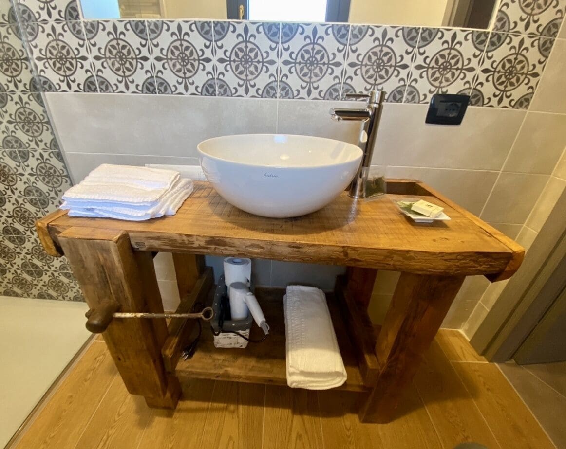 A wooden vanity with a white basin, towel holder, and a towel dispenser.