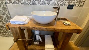 A wooden vanity with a white basin, towel holder, and a towel dispenser.