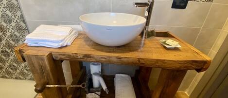 A wooden vanity with a white basin, towel holder, and a towel dispenser.