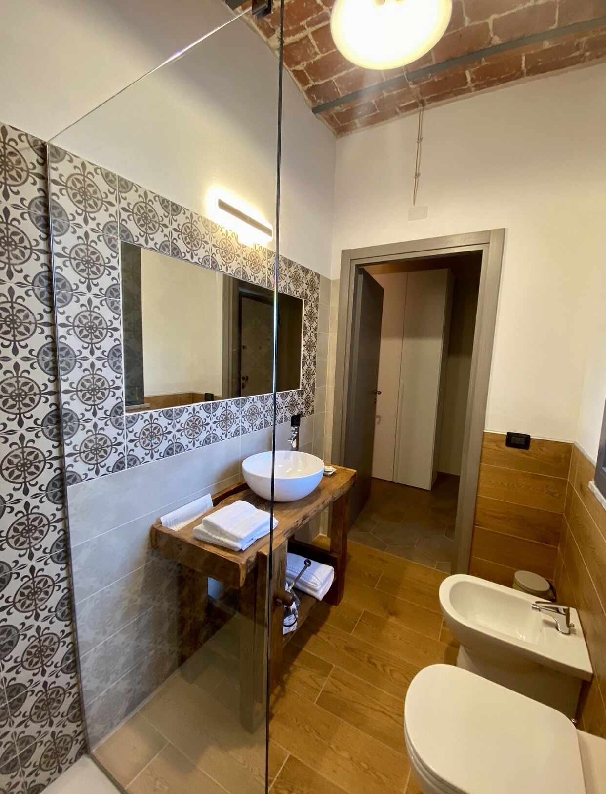 Un baño moderno con un espejo grande, un tocador de madera, un lavabo blanco y una bañera.