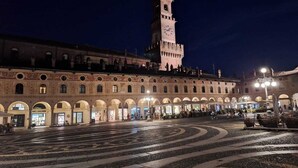 A historic building with a clock tower, arched walkways, and a paved plaza. - Cascina Mora Bassa (Vigevano)