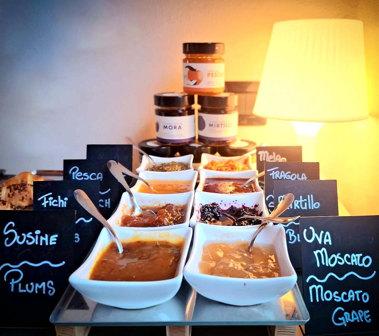 A food display with various dips and condiments, including labels for 'Pesca', 'Tich', 'Susine', and 'Plums'.