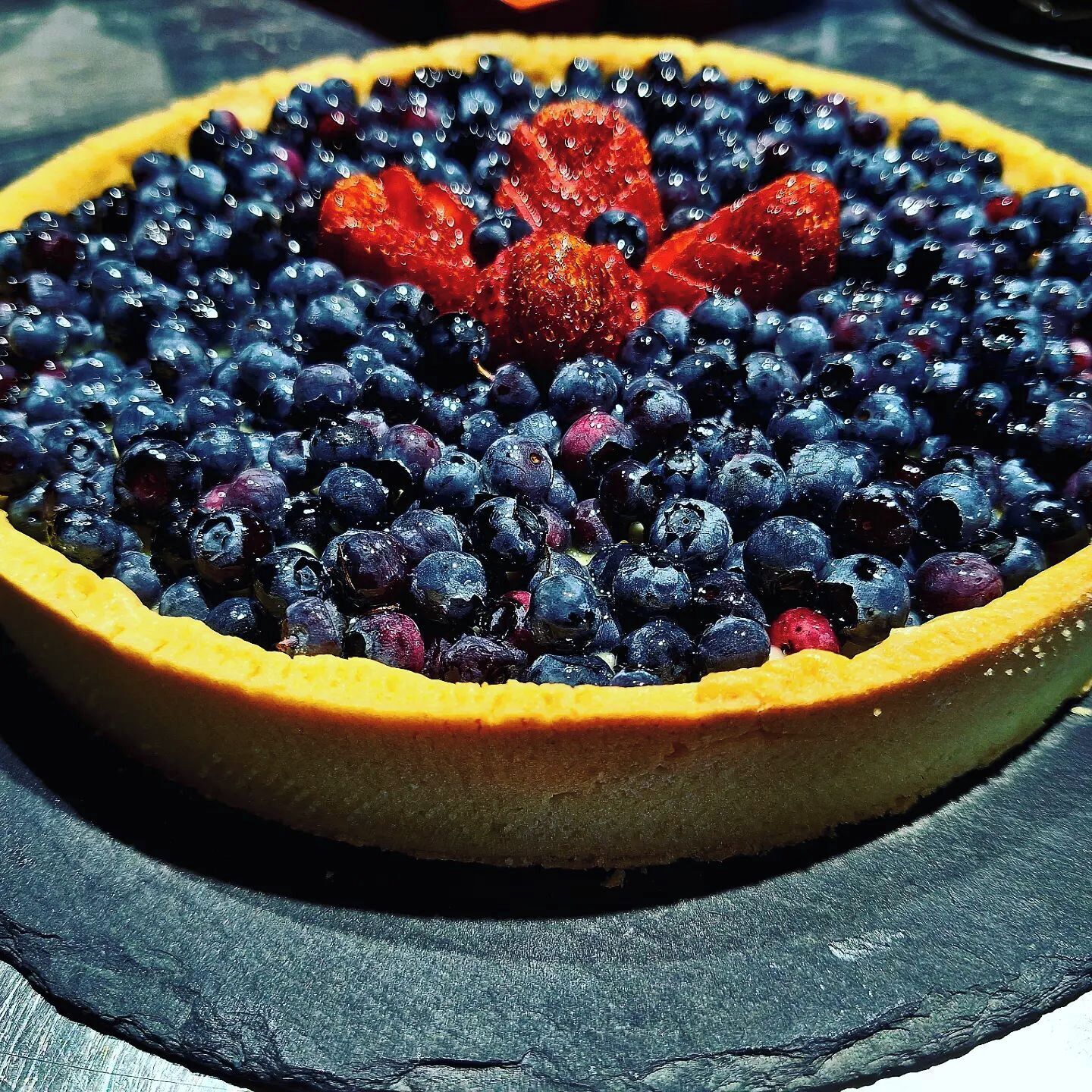 Une tarte aux myrtilles, avec une croûte dorée et des myrtilles fraîches sur le dessus.