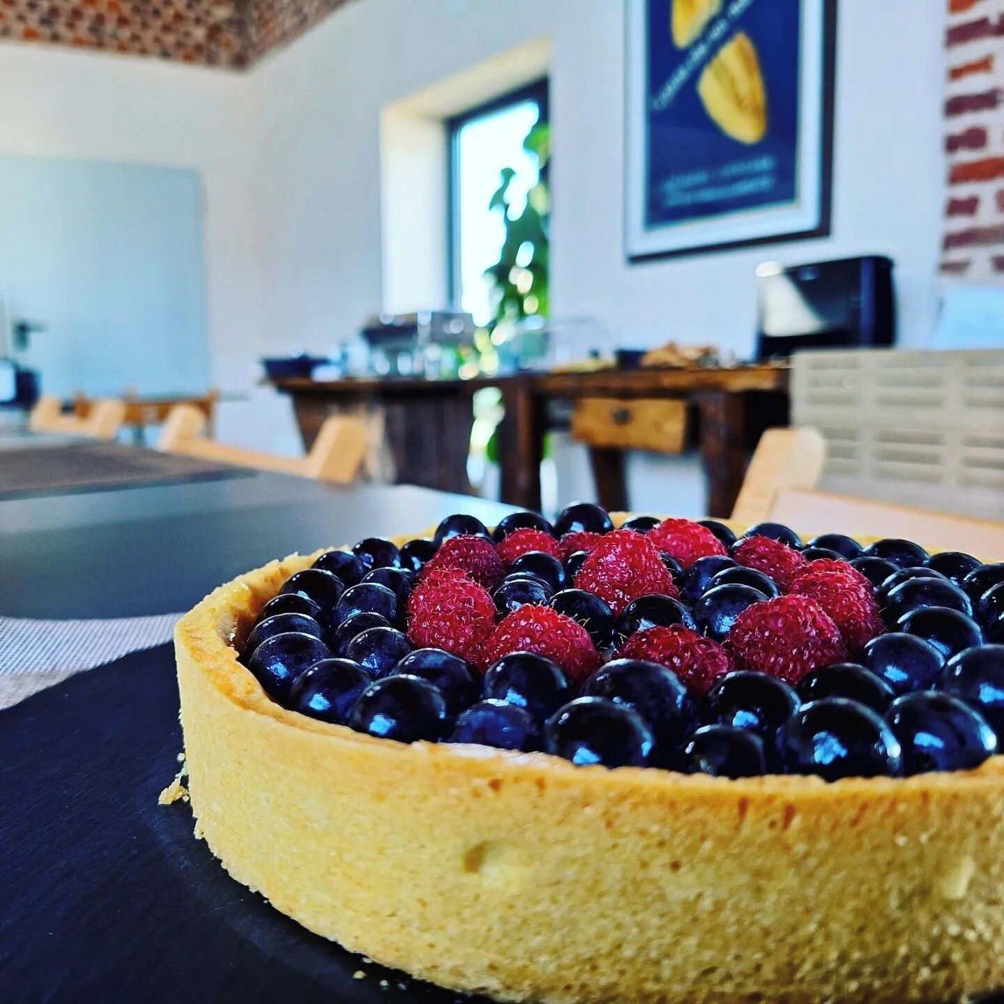 A dessert with berries on a plate in a room with a desk and a window.