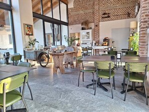 A spacious dining area with high ceilings, exposed brick walls, and large windows. - Cascina Mora Bassa (Vigevano)