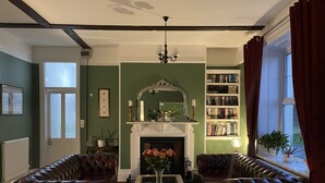 A living room with a fireplace, leather sofas, a coffee table, and a bookshelf. - Moorlands (Barnstaple)