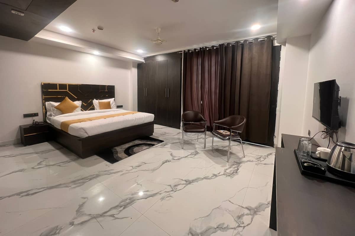 A modern hotel room with a large bed, a desk, a chair, and a TV.
