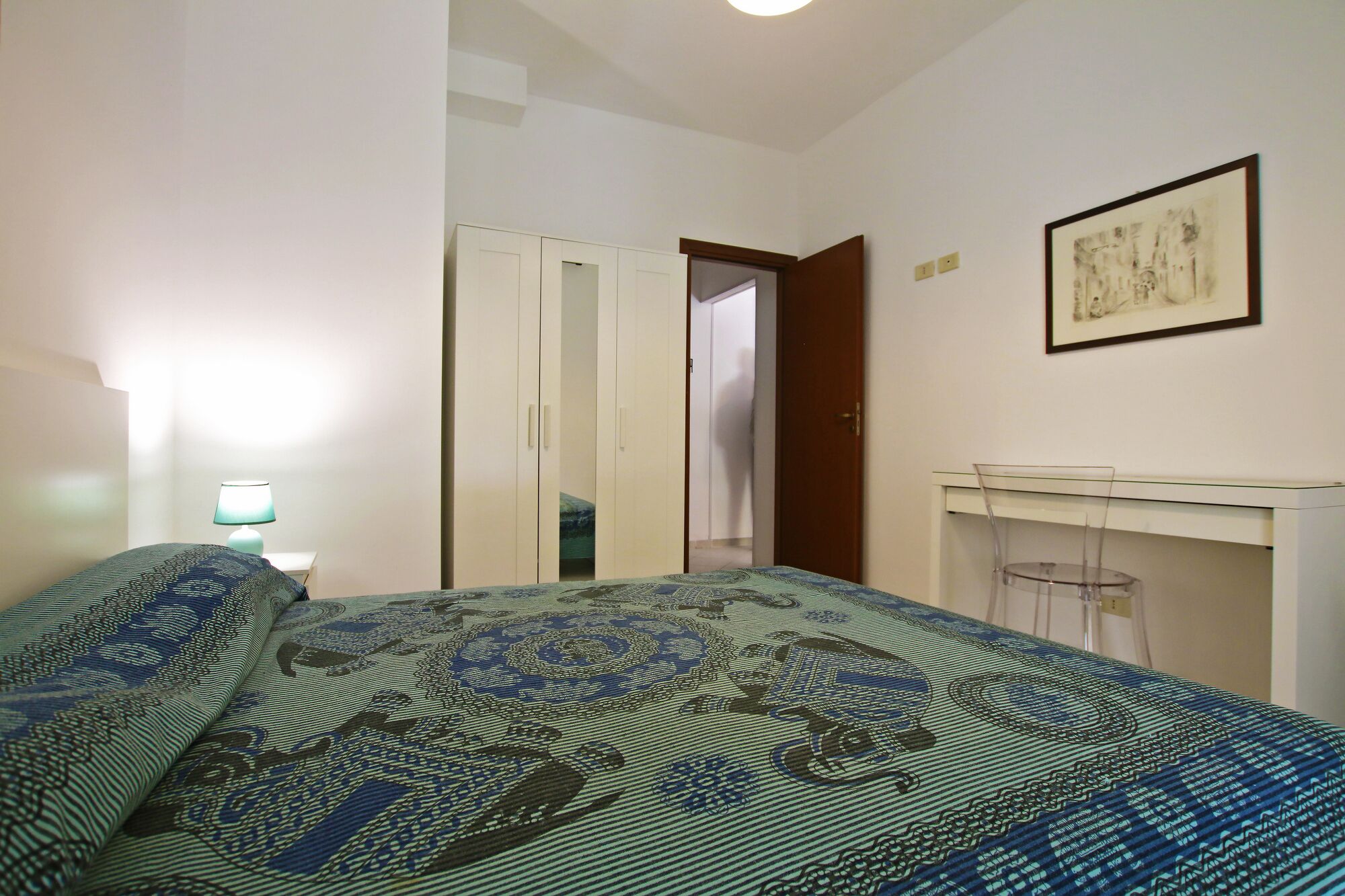 Quarto com cama, guarda-roupa, escrivaninha e cadeira.