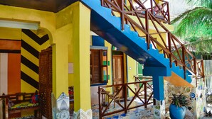 A colorful building with a staircase, a wooden bench, and a potted plant. - COCCOBELLO ZANZIBAR (Kendwa)