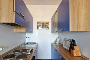 Køleskab, kogeplade, køkkentøj/tallerkener/redskaber, spisebord
