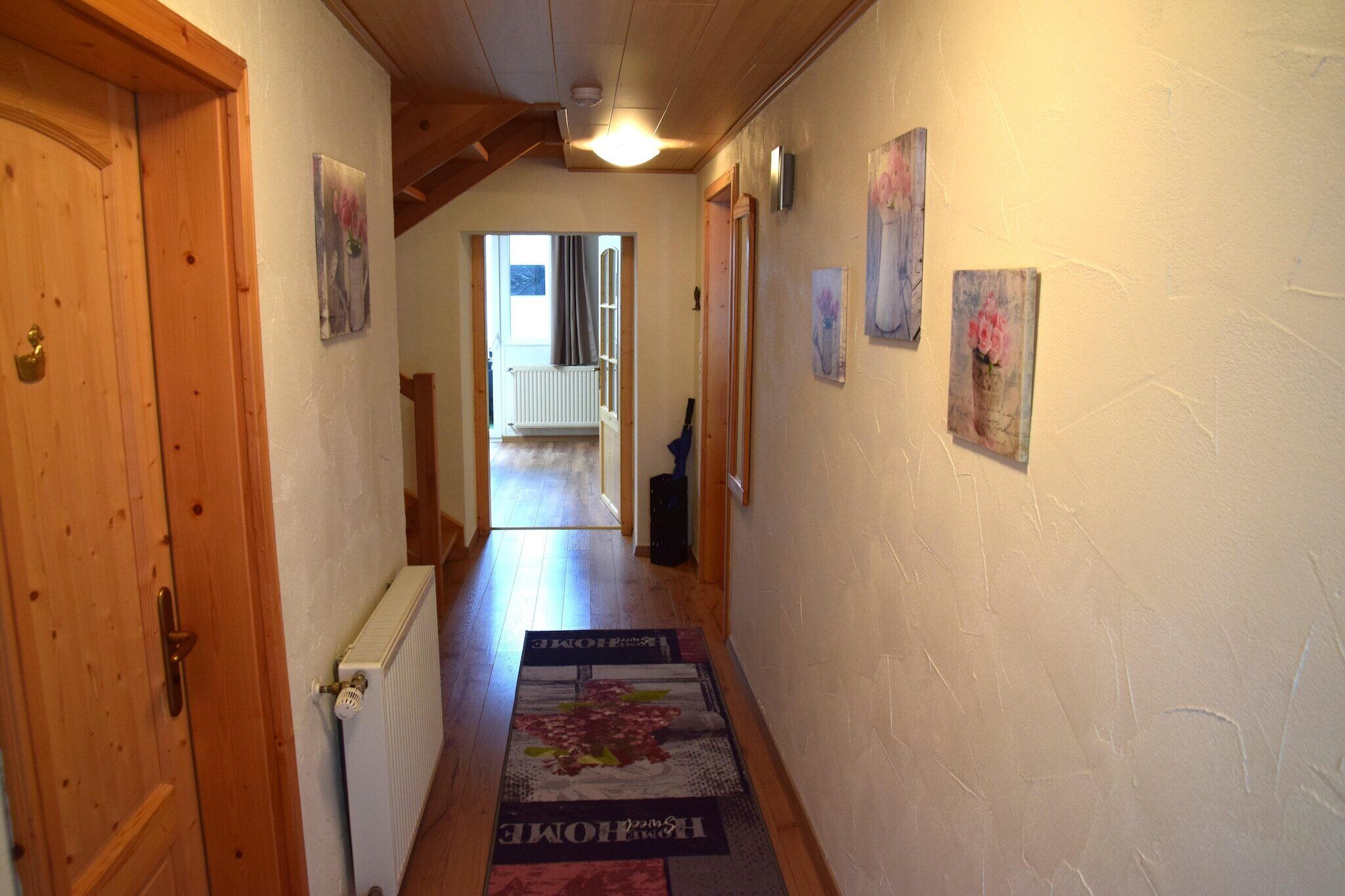 Un couloir avec des portes en bois, un radiateur et un paillasson.