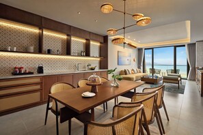 A modern kitchen with a dining area, large windows with a view of the sea, and wicker furniture. - Angsana Quan Lan, Ha Long Bay (Van Don)