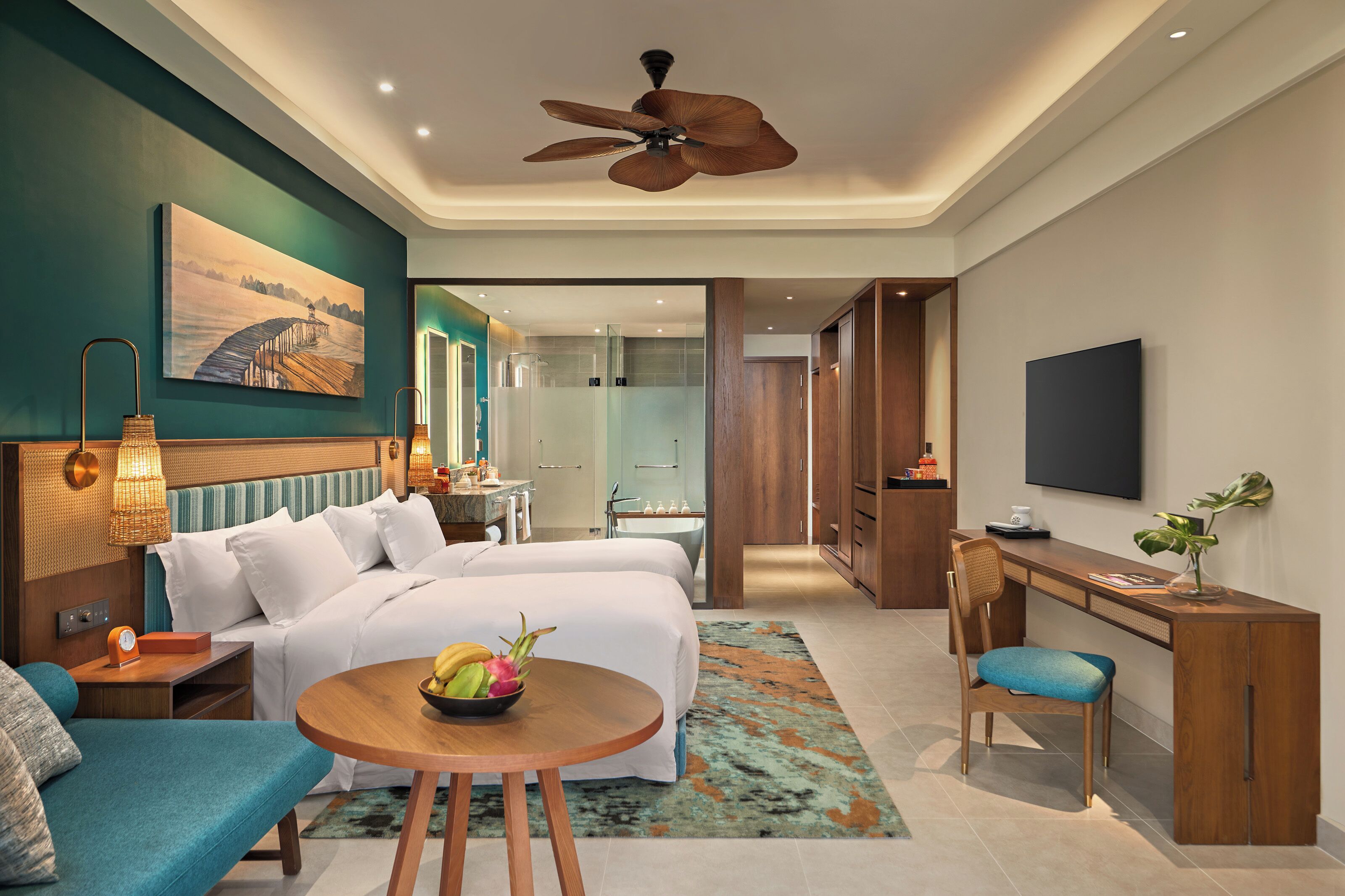 A modern hotel room with a bed, desk, seating area, and a TV.