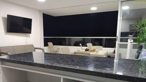 A modern kitchen with a granite countertop, white cabinetry, and a flat-screen TV mounted on the wall. - ¡Te va a Encantar! Disole 1104 (Santa Fé de Antioquia)