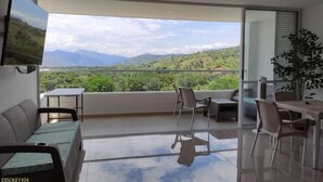 A modern living room with a balcony, a sofa, a TV, and a dining area with chairs and a table. - ¡Te va a Encantar! Disole 1104 (Santa Fé de Antioquia)