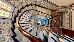 Una escalera en espiral con barandilla de madera y un papel tapiz con diseño.