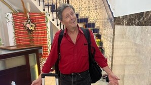 Un vestíbulo de hotel con una escalera, una recepción y una maleta roja.