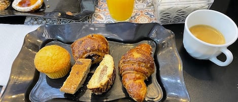 A breakfast tray with pastries, a glass of orange juice, and a cup of coffee.