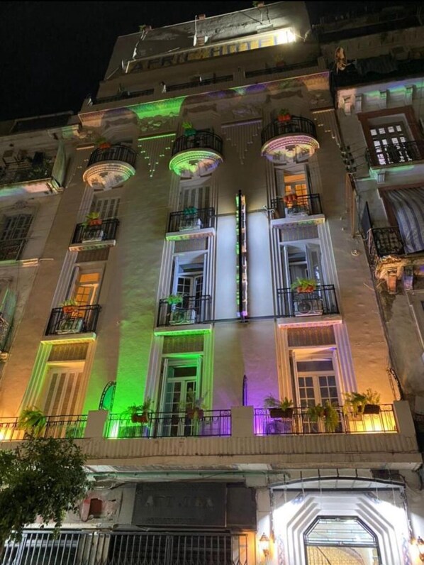 Um edifício com várias andares, varandas, janelas amplas e uma entrada central.