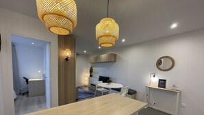 A modern kitchen with a wooden countertop, a round dining table, and two hanging wicker pendant lights. - Sunset Cocoon T2 46m2 Proche Centre Ville (Villejust)