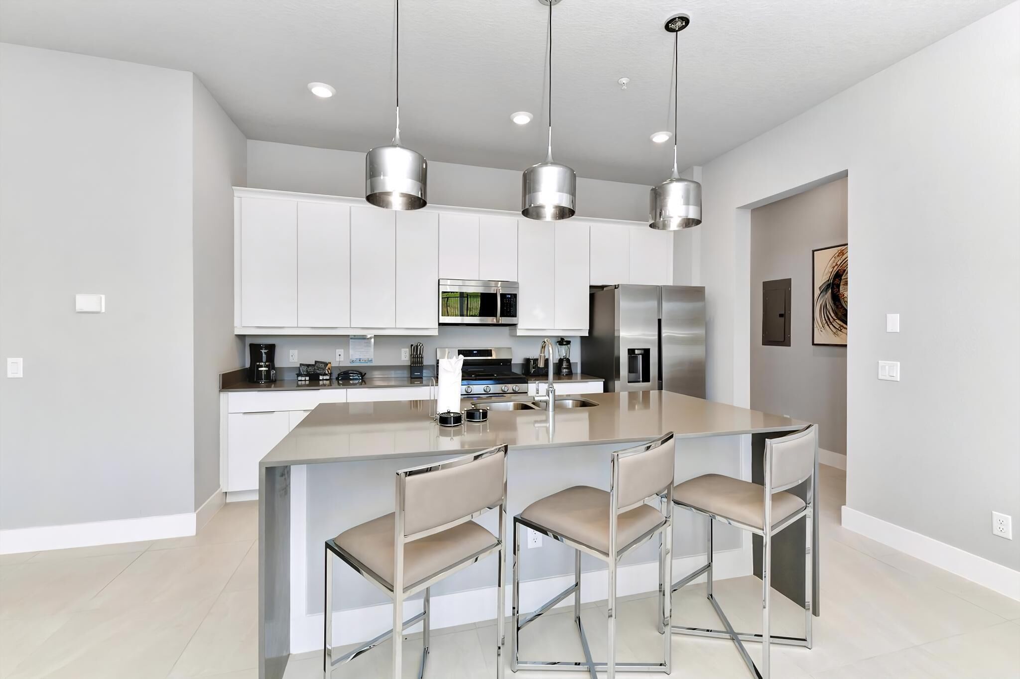 A modern kitchen with white cabinets, stainless steel appliances, and a central island with bar stools.