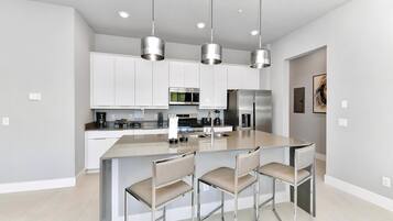 A modern kitchen with white cabinets, stainless steel appliances, and a central island with bar stools.