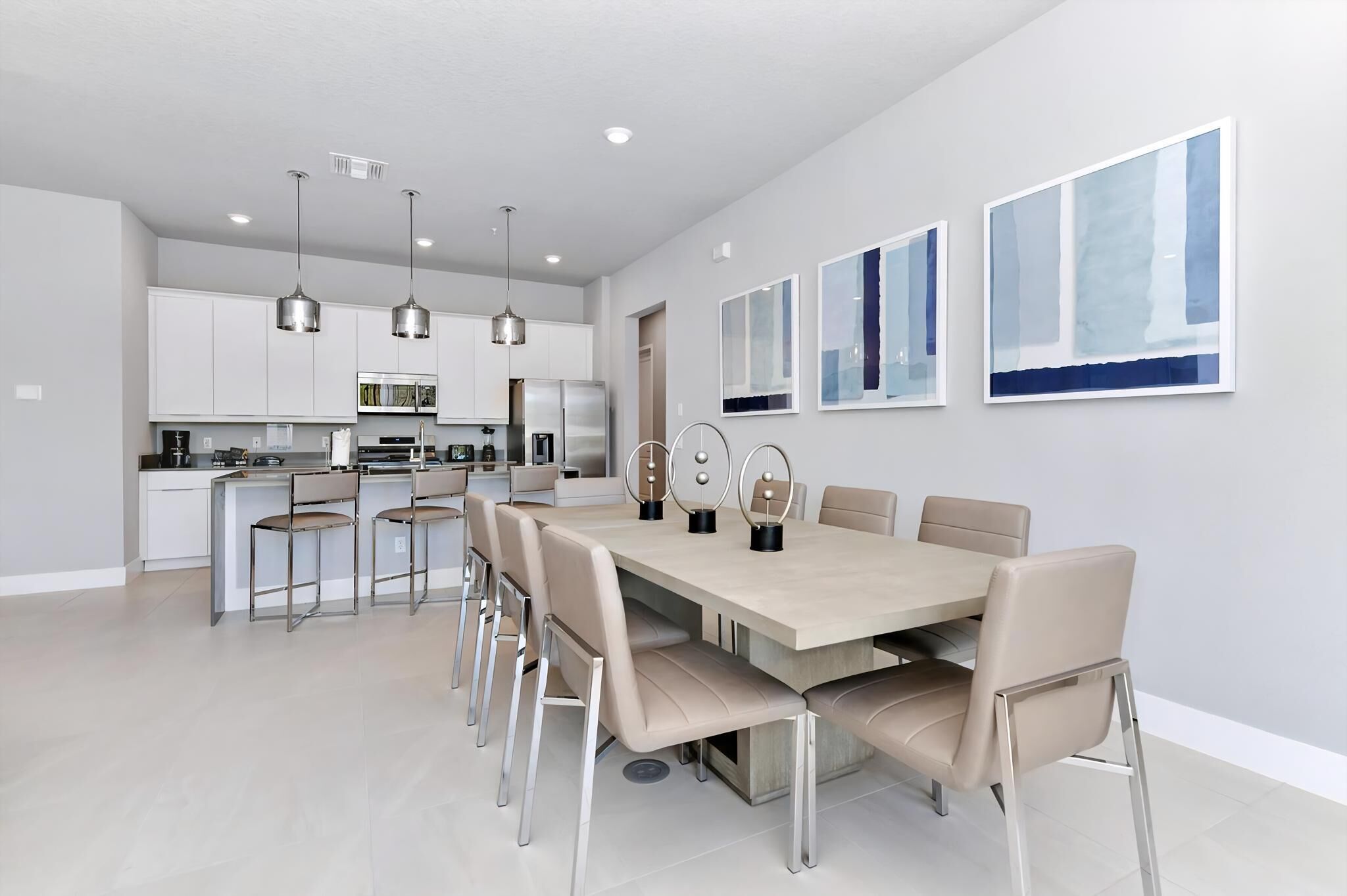 A modern kitchen with white cabinets, stainless steel appliances, and pendant lighting.
