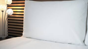 A neatly made bed with a white pillow and a wooden headboard.