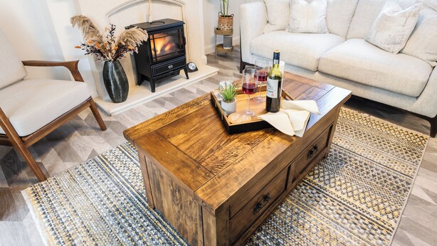 A cozy living room with a fireplace, a sofa, a coffee table with decorative items, and a wooden chair. - Hampshire Charming House (Lincoln)