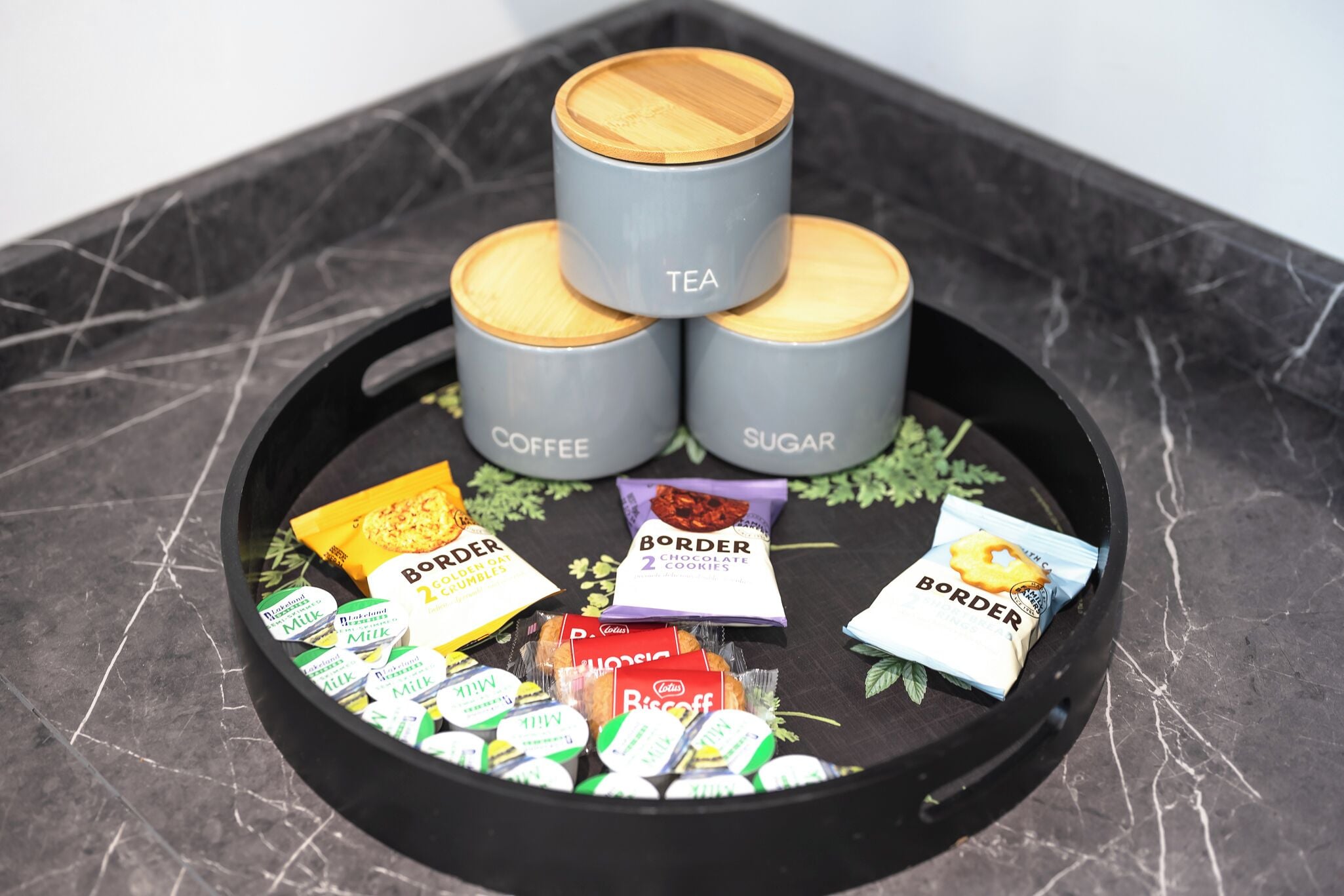 A tray with tea, coffee, and sugar containers, along with various snacks and packaged goods.
