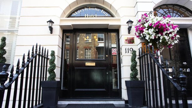 Ingången till Marylebone Inn Hotel med en svart dörr, en skylt ovanför dörren och nummer 119 på väggen.