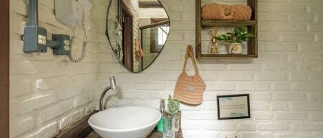 A bathroom with a white sink, a mirror, a towel rack, and a shelf with towels.