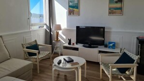 Ett vardagsrum med en soffa, två fåtöljer, ett soffbord, en tv och konstverk på väggarna.