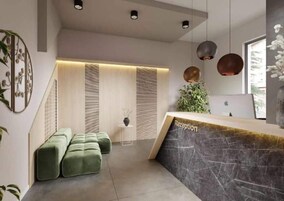 Una moderna zona de recepción con mostrador de mármol, asientos verdes y una planta.