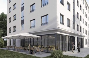 Un edificio moderno con fachada plana, múltiples ventanales y una zona de estar exterior cubierta con mesas y sillas.