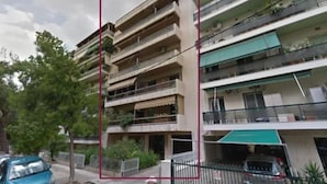 A multi-story residential building with balconies, a gated parking area, and a street view. - Afroditi Suite (Nea Smirni)