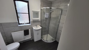 A modern bathroom with a toilet, sink, and glass-enclosed shower. - Heart of Lincoln City, 3 Bedrooms, Sleeps 4 Guests (Lincoln)