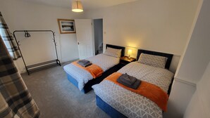 A hotel room with two beds, a wardrobe, a coat rack, and a framed picture on the wall. - Heart of Lincoln City, 3 Bedrooms, Sleeps 4 Guests (Lincoln)