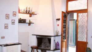 A room with a fireplace, wooden shelves with various items, a door with a decorative screen, and a tiled floor. - Ca du Paraxo (Levanto)