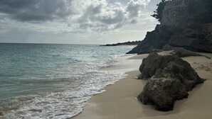 A beach with a rocky outcrop and a building on a cliff. - Holiday House in beautiful Cupecoy (Cupecoy Beach Club)
