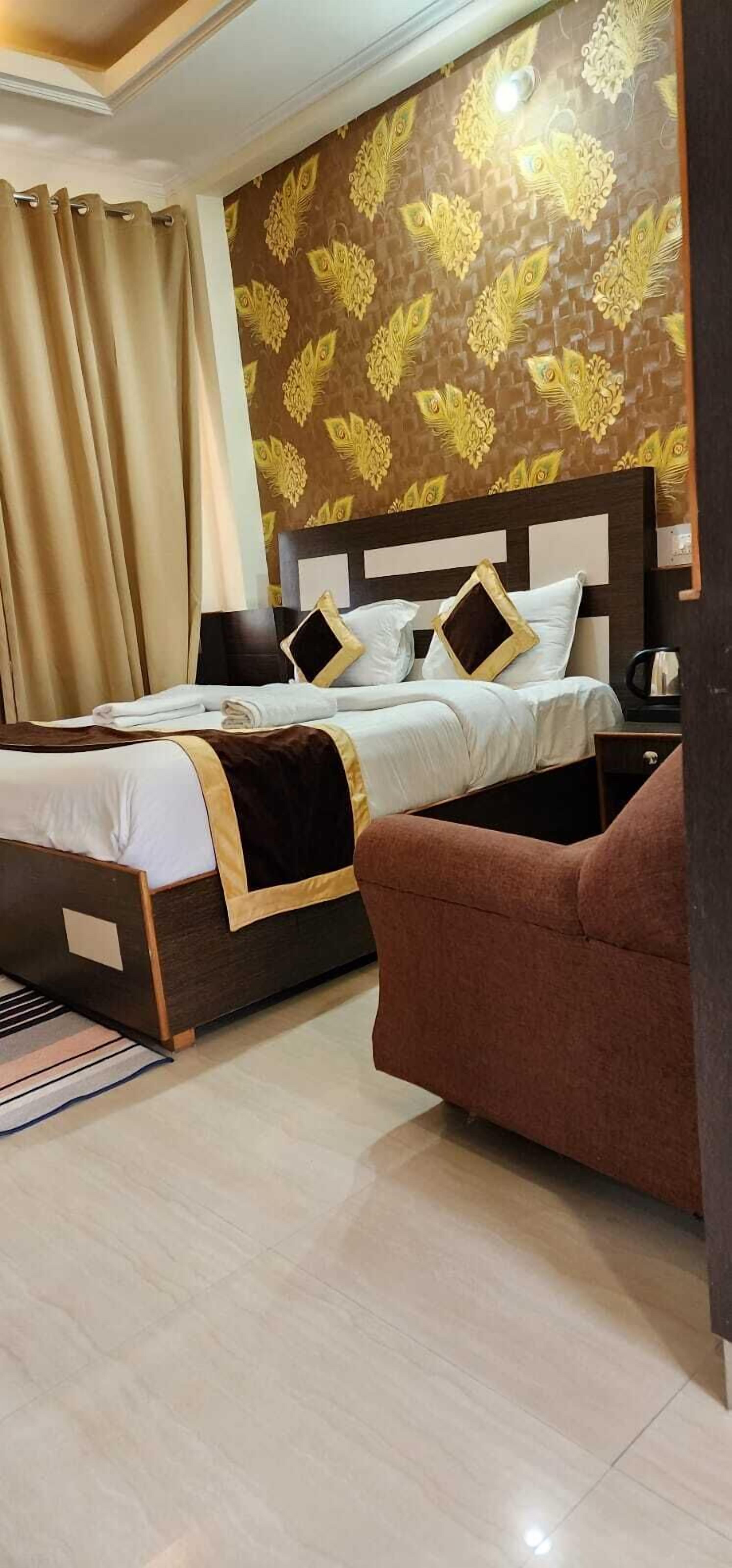 A hotel room with a bed, a brown armchair, and a patterned wallpaper.