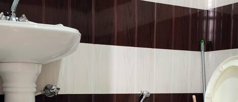 Un baño con lavamanos pedestal, inodoro y bidé.