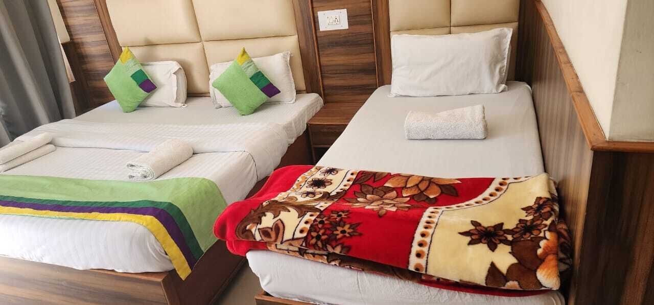 Two single beds with headboards, a green and a red floral bedspread, and white pillows.